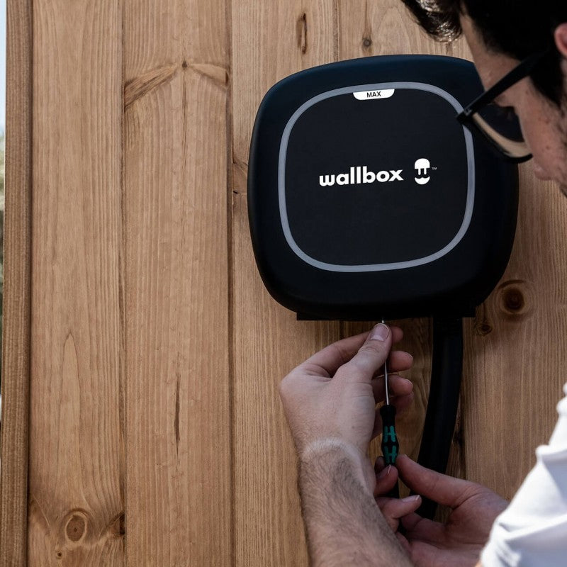 Wallbox Pulsar Max noire installée sur un mur en bois.